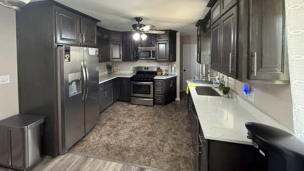 A compact kitchen with dark cabinets, a stainless steel refrigerator, a microwave, and a gas stove.