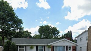 A two-story house with a front yard, a small garden, and a driveway.