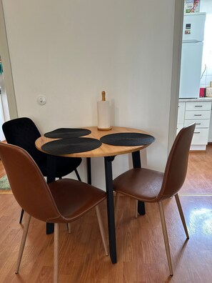 Un coin repas comprenant une table ronde, deux chaises marron et un élément décoratif central.