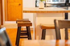 A kitchen with wooden stools, a white countertop, and a vase with flowers.