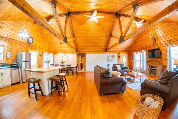 A spacious log cabin interior with a kitchen, dining area, and living room.
