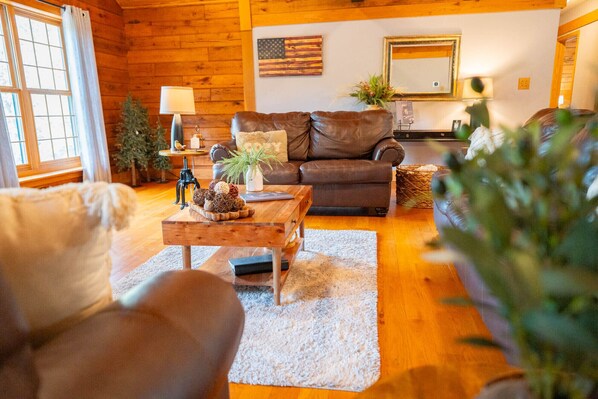A cozy living room with a leather sofa, a wooden coffee table, and a fireplace.