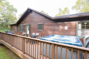 Eine Holzhütte mit Whirlpool, Terrasse und Sitzgelegenheit im Freien.