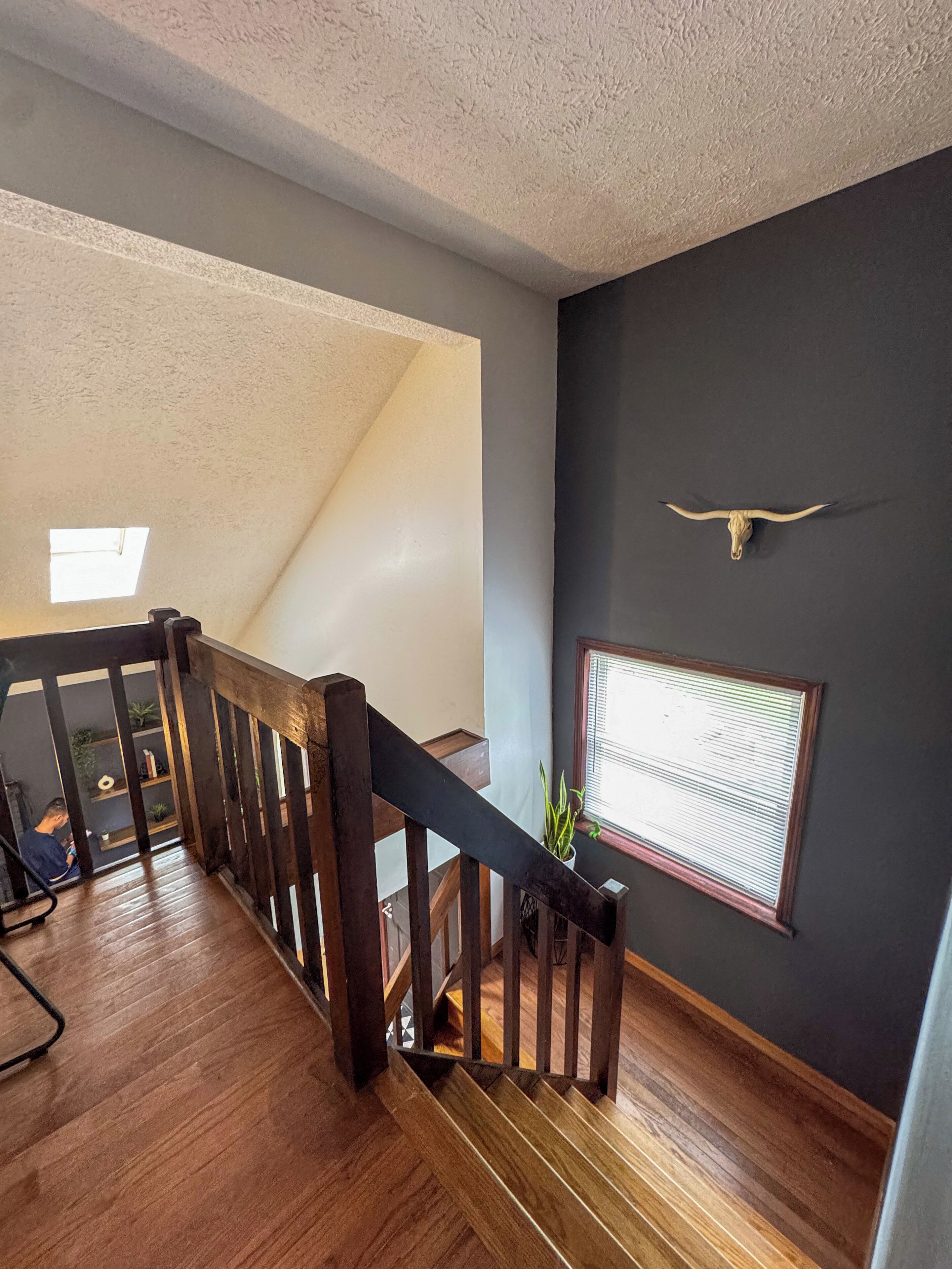 A wooden staircase with a dark wall and a cow skull decoration.