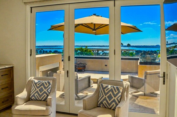 A balcony with two chairs, a table, and a large umbrella.