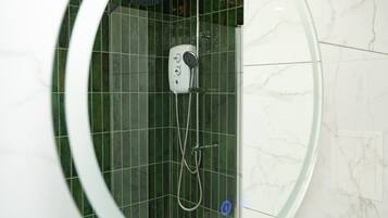 Une douche moderne dotée d’un pommeau de douche à main et d’un pommeau de douche fixe fixé au mur, le tout installé sur un mur recouvert de carreaux verts.