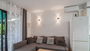 A modern living room with a grey sectional sofa, a wooden coffee table, and a white refrigerator.