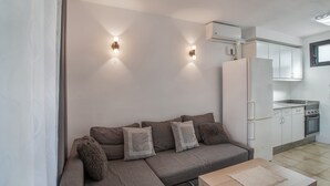 A modern living room with a sofa, a coffee table, and a kitchen area with cabinets and appliances.