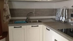 A kitchen with white cabinets, a stainless steel sink, and a stove.