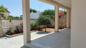 A covered outdoor area with a tiled floor, stone walls, and a small tree.