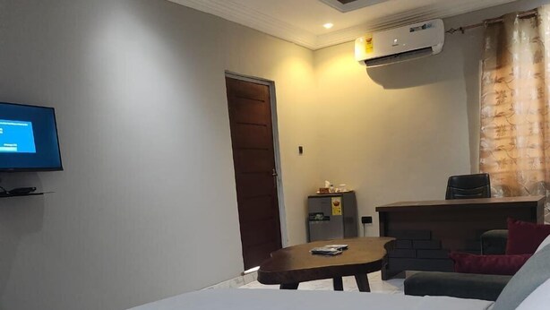 A hotel room with a bed, a TV, a desk, and a chair. - Tetra Jungle Lodge (Akropong)