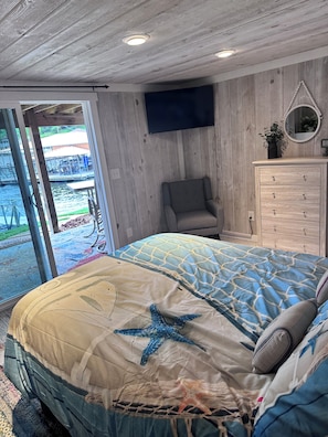 A bedroom with a bed, a chair, a dresser, and a view of a dock and water. - Peggy's Paradise- Like NEW- 3 Bdrm Lakefront Home on Gravois Arm, Lake of Ozarks (Gravois Mills)