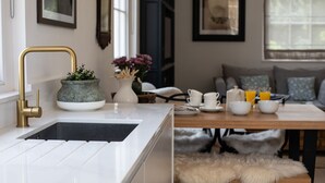 Eine moderne Küche mit einem goldfarbenen Wasserhahn, einer weißen Spüle und einem Blumentopf.