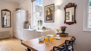 Eine moderne Küche mit weißen Schränken, einem Holzespeisetisch und einem großen Fenster.