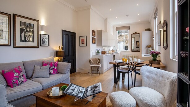 Ein modernes Wohnzimmer mit einem grauen Sofa, einem Couchtisch und einem Essbereich mit einem Holztisch und Stühlen.