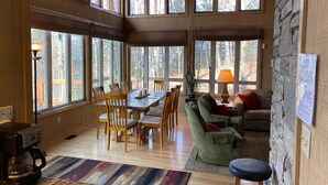 A spacious living area with a wooden dining table, chairs, a green sofa, and a stone accent wall.