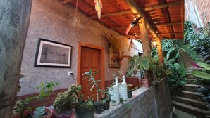 A covered outdoor area with a wooden door, potted plants, and hanging decorations.
