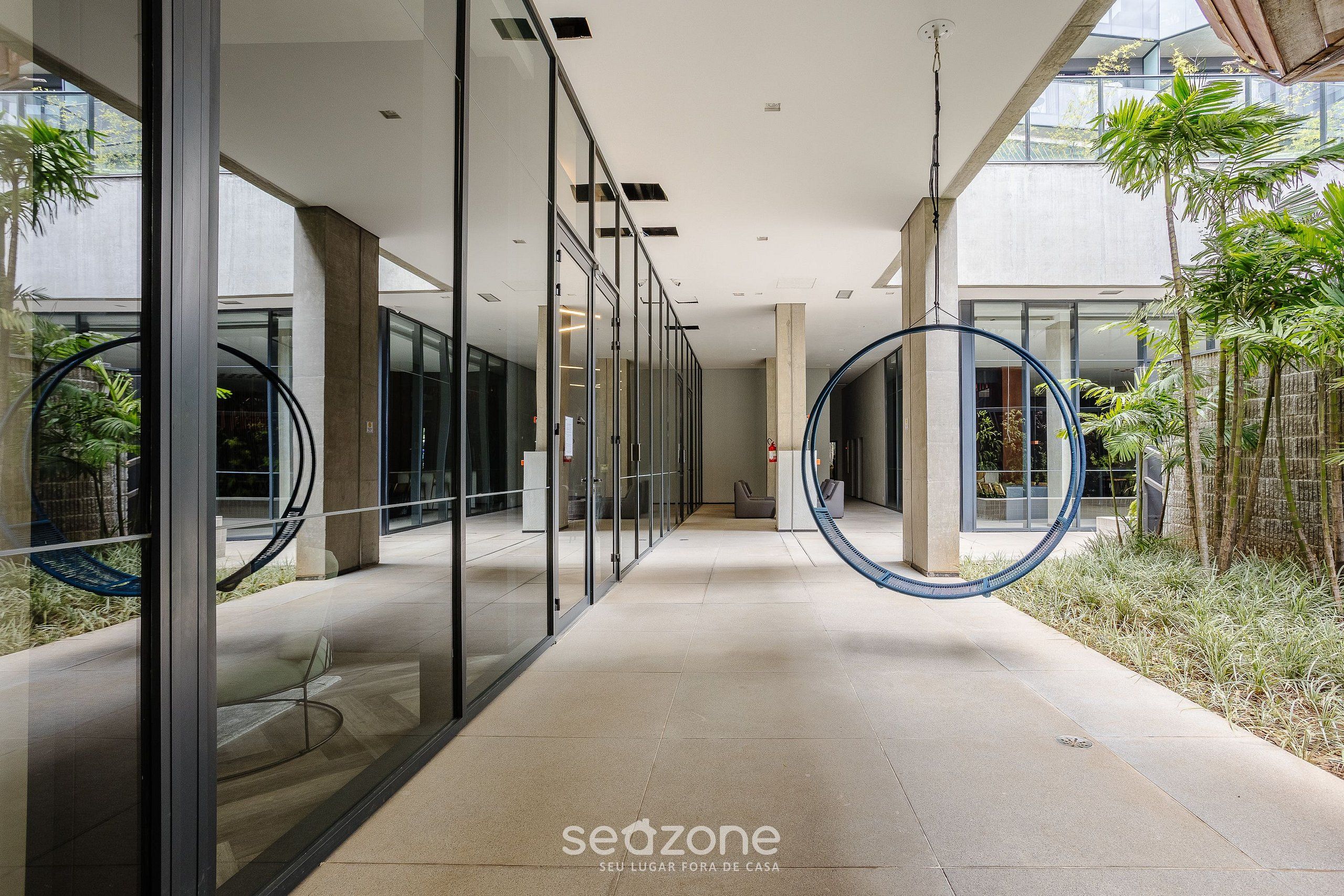 Un couloir intérieur moderne avec des murs en verre, un plafond incurvé et un élément circulaire central.