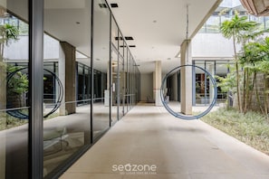 A modern interior corridor with glass walls, a curved ceiling, and a central circular feature. - Modern Studio in Itaim Bibi-sp Cia2313 (São Paulo)