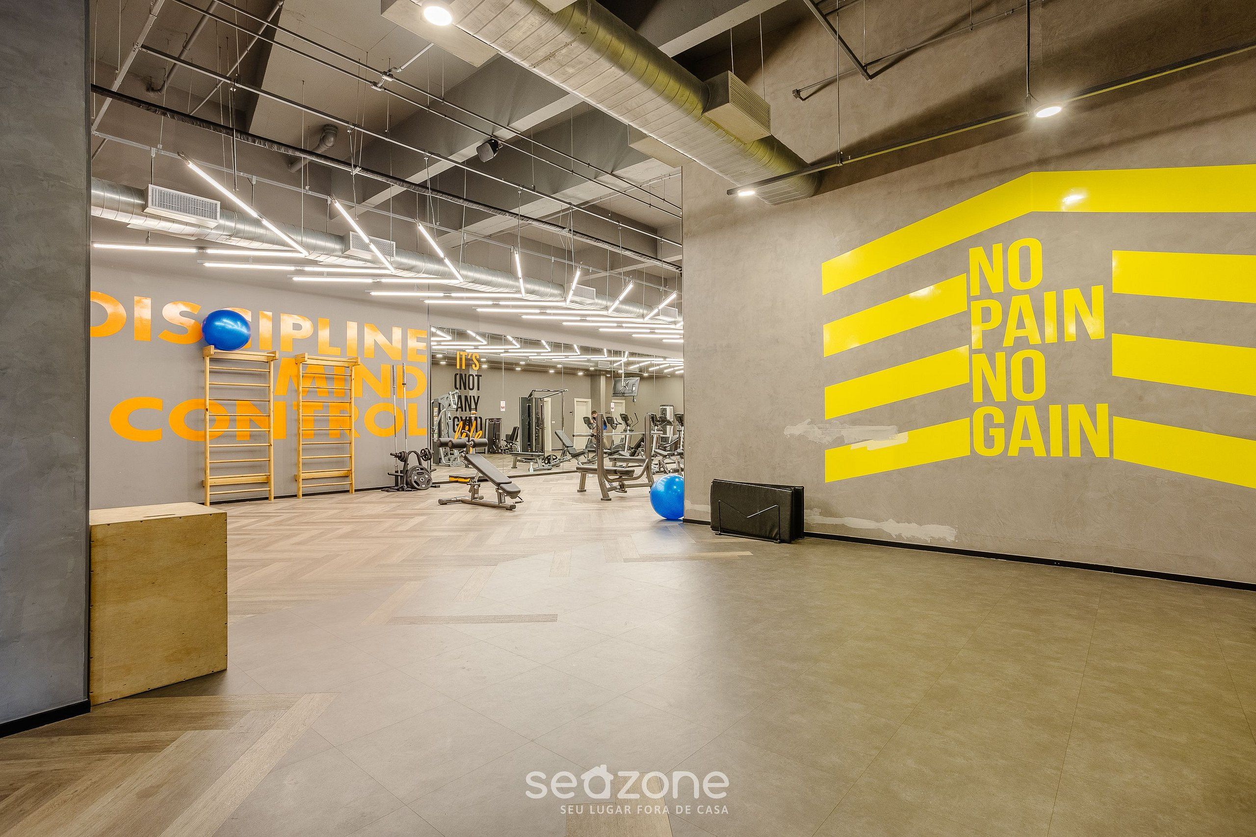 A gym with exercise equipment, a motivational wall with 'NO PAIN NO GAIN' slogan, and a 'SEAZONE' logo.