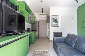 A modern kitchen with green cabinets, a flat-screen TV, and a dining area with a sofa. - Lovely 270 m From Oscar Freire Subway Coe0406 (São Paulo)