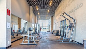 A modern gym with various exercise equipment, large windows, and a high ceiling with linear lighting. - Beautiful Studio 270m Oscar Freire Subway Coe0406 (São Paulo)