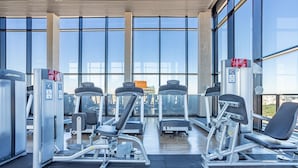 Ein Fitnessstudio mit verschiedenen Trainingsgeräten, großen Fenstern und einem modernen Design.
