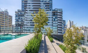 Un área de piscina en la azotea con vistas despejadas a edificios modernos al fondo.
