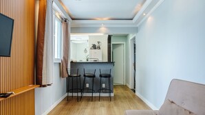 A compact living space with a kitchenette, a dining area with bar stools, and a seating area with a sofa. - Charming Apartment in Pinheiros - Cot0081 (São Paulo)