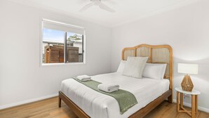 Une chambre à coucher avec un lit, une fenêtre, une table de chevet et un ventilateur de plafond.