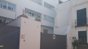 A gated courtyard with a building number 12, a metal gate, and a dog.