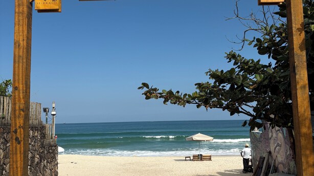A wooden archway with "Corona" and "Praia de Marésias" signage, leading to a beach with a mural and beach chairs. - House with 4 bedrooms in the best gated community in Maresias, 150 meters from the beach. (Maresias São Sebastião)