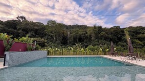 A rectangular swimming pool with tiled edges, surrounded by a tiled deck. - House with 4 bedrooms in the best gated community in Maresias, 150 meters from the beach. (Maresias São Sebastião)