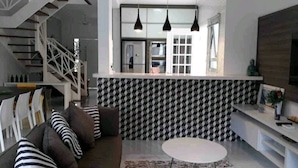 A modern living room with a staircase, a dining area, and a kitchen with a patterned backsplash. - House with 4 bedrooms in the best gated community in Maresias, 150 meters from the beach. (Maresias São Sebastião)