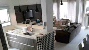 A modern kitchen with a central island, a dining area with a table and chairs, and a living room with a sofa and curtains. - House with 4 bedrooms in the best gated community in Maresias, 150 meters from the beach. (Maresias São Sebastião)