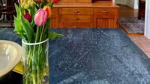Una habitación con un armario de madera, un jarrón de tulipanes y un comedor.