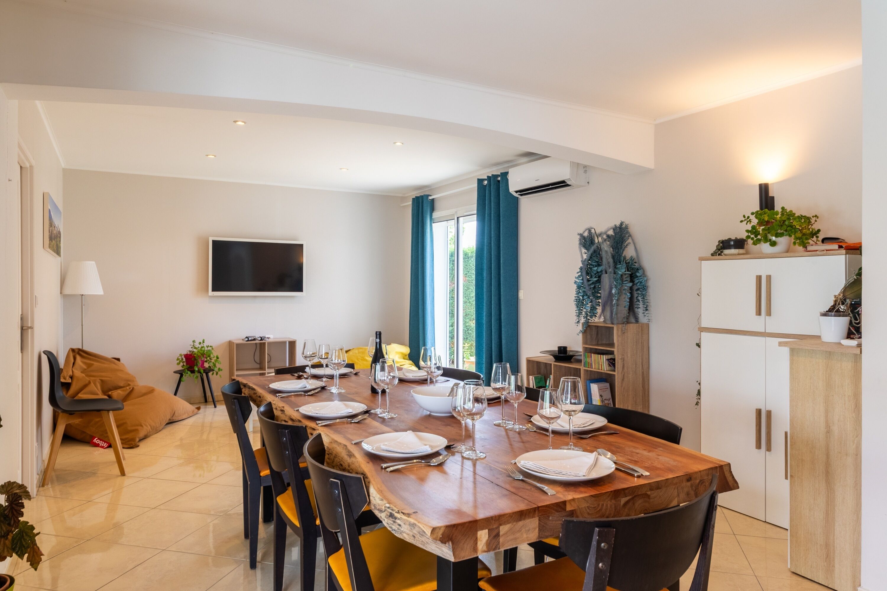 Un coin repas avec une table en bois, dressée pour six personnes, entourée de chaises.