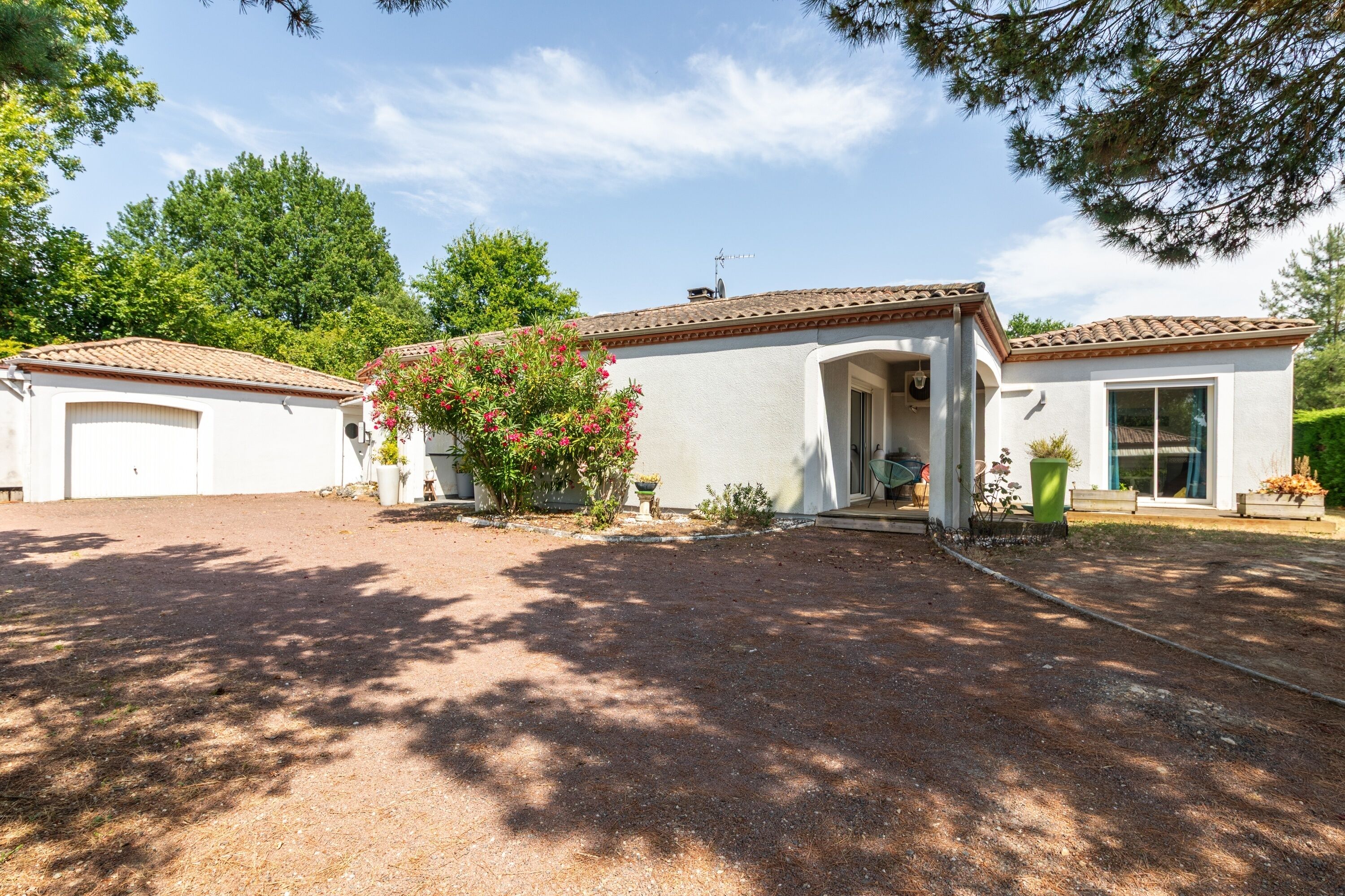 A two-story house with a covered porch, a garage, and a well-maintained garden with flowering plants.