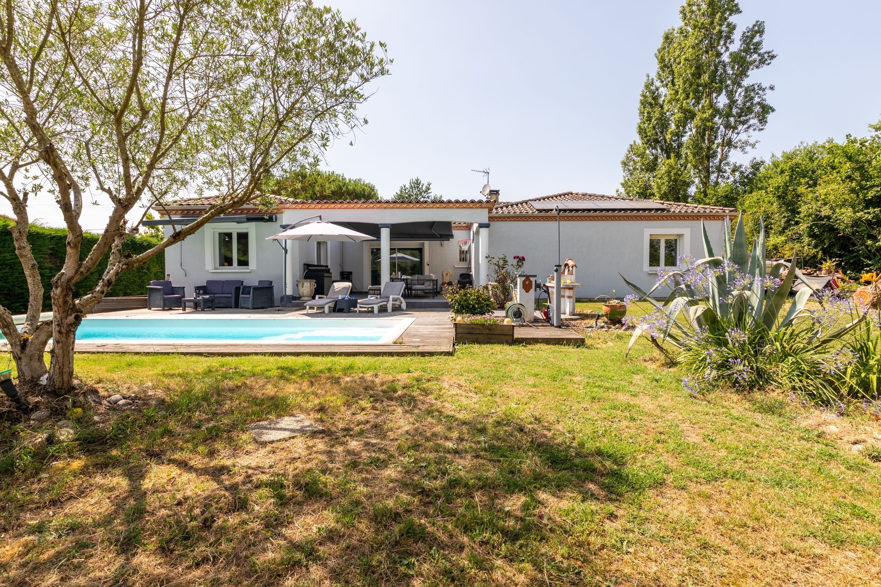 Une maison avec une piscine, un espace extérieur aménagé et un jardin.