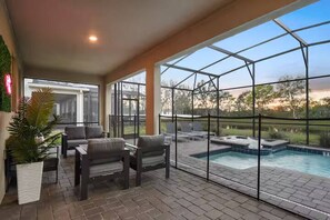 An indoor pool area with a glass enclosure, seating, and a hot tub.