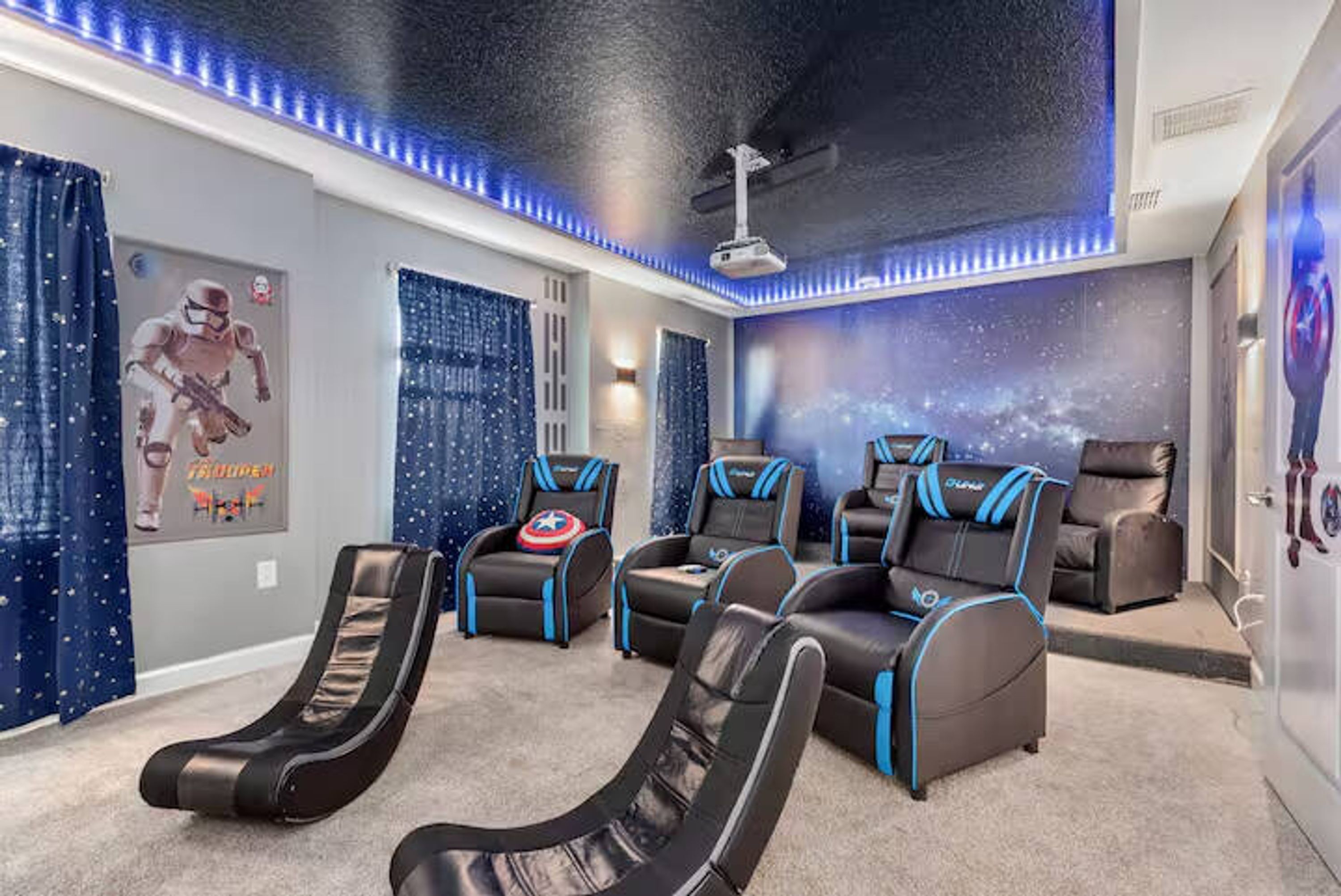 A room with a ceiling projector, reclining chairs, and a wall mural.
