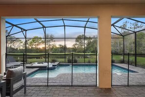 A covered outdoor swimming pool with a hot tub, surrounded by a patio area with seating.