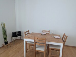 A dining table with four chairs, a small potted plant, and a radio on a side table.