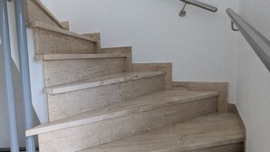 Escada com corrimão de metal e degraus bege.