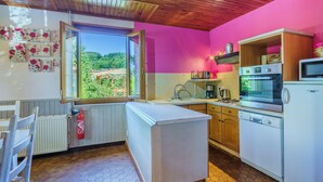 Une cuisine compacte avec des meubles en bois, un plan de travail blanc et une vue sur un paysage verdoyant par une fenêtre.