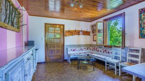 Une pièce avec un plafond en bois, un banc recouvert d’un tissu à motifs floraux, une porte en bois et un sol carrelé.