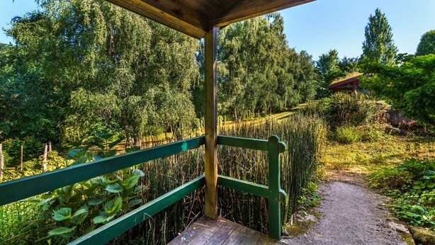 En træpergola med en grussti, der snor sig gennem en frodig have.