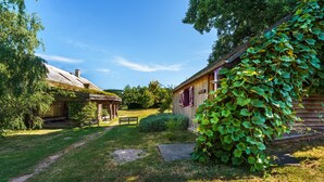 A rustic wooden house with a thatched roof and ivy-covered exterior.