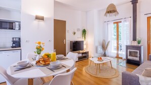 Una sala de estar moderna con chimenea, un comedor con mobiliario blanco y una cocina con microondas.