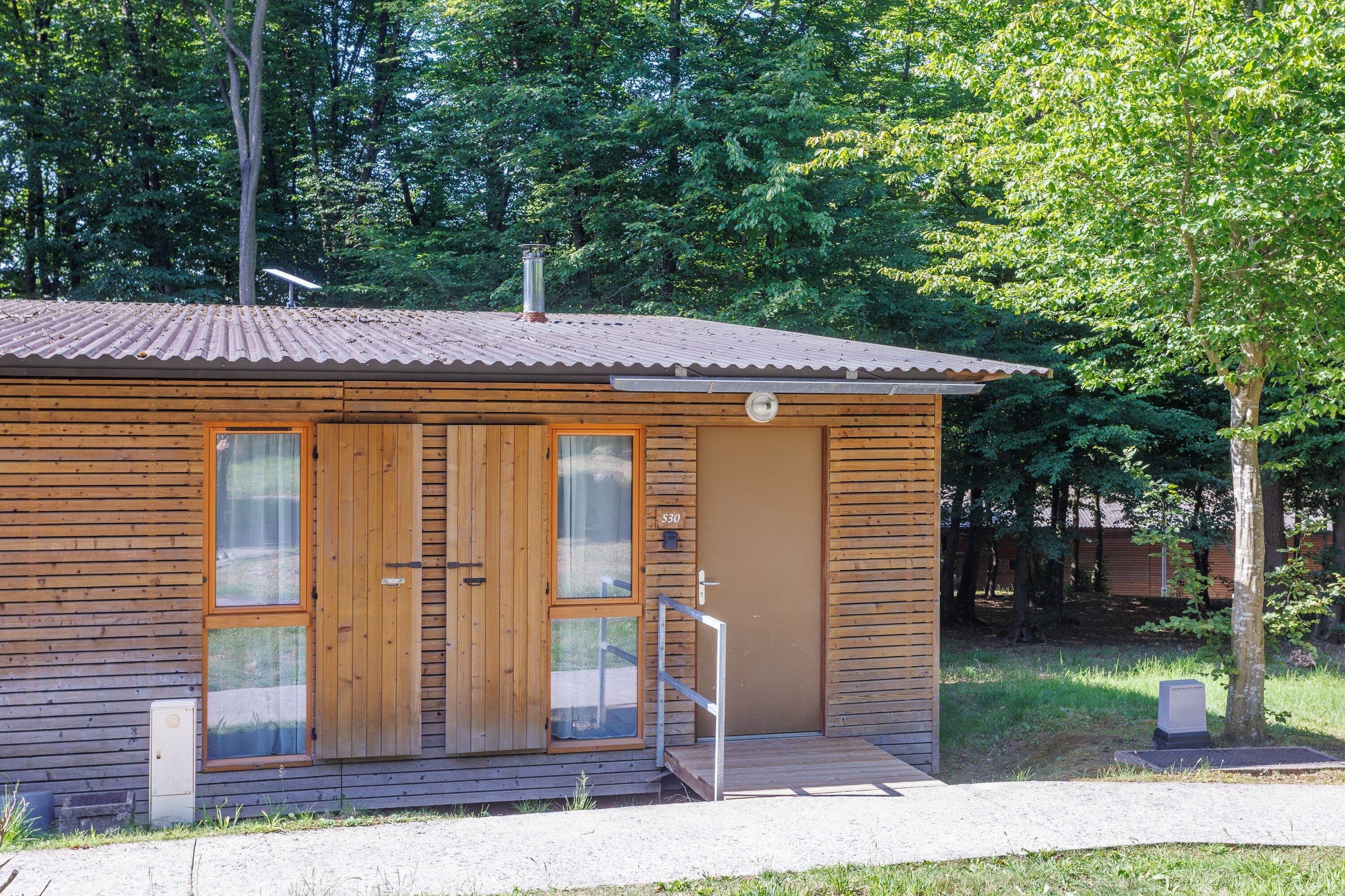 Une petite cabane en bois, avec un toit en métal, une porte en bois et un petit porche.